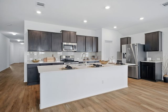 601 Sassafras St, Hutto, TX 78634 - kitchen with stainless steel appliances, a sink, light wood finished floors, decorative backsplash, and recessed lighting