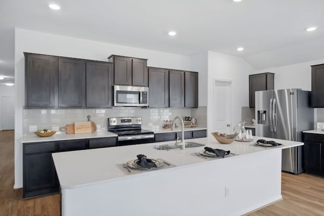 601 Sassafras St, Hutto, TX 78634 - kitchen featuring appliances with stainless steel finishes, a sink, a center island with sink, decorative backsplash, and light countertops