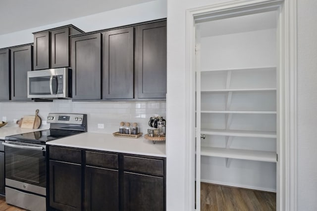 601 Sassafras St, Hutto, TX 78634 - kitchen featuring stainless steel appliances, light countertops, wood finished floors, and decorative backsplash