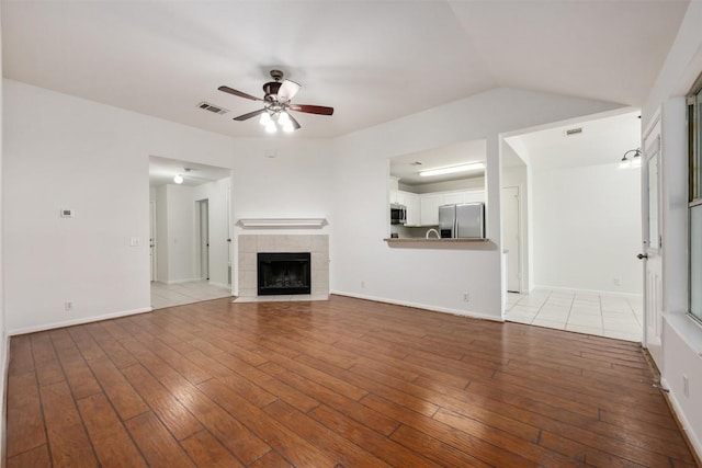 223 Keystone Loop, Kyle, TX 78640 - unfurnished living room featuring ceiling fan, wood-type flooring, and a tile fireplace
