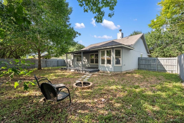 223 Keystone Loop, Kyle, TX 78640 - rear view of property with a fenced backyard, a chimney, a fire pit, and roof with shingles