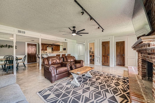 3610 Quiette Dr, Austin, TX 78754 - living area with a decorative wall, ceiling fan, a textured ceiling, a brick fireplace, and rail lighting