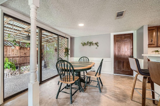 3610 Quiette Dr, Austin, TX 78754 - dining area featuring a textured ceiling, healthy amount of natural light, finished concrete floors, wainscoting, and recessed lighting