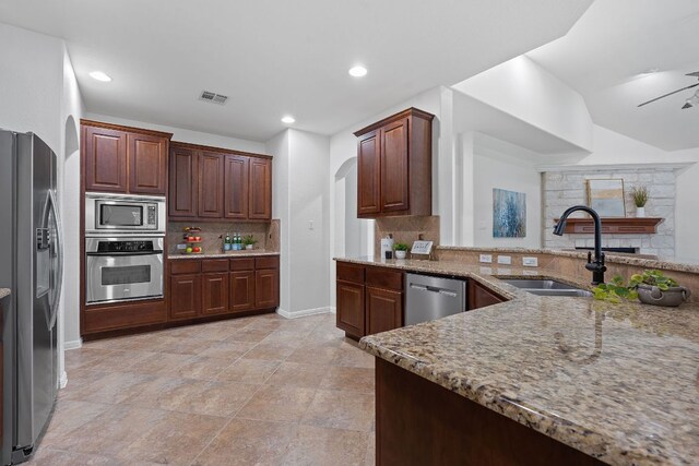 16413 Broadbay Dr, Austin, TX 78717 - kitchen with stainless steel appliances, tasteful backsplash, light stone counters, recessed lighting, and arched walkways