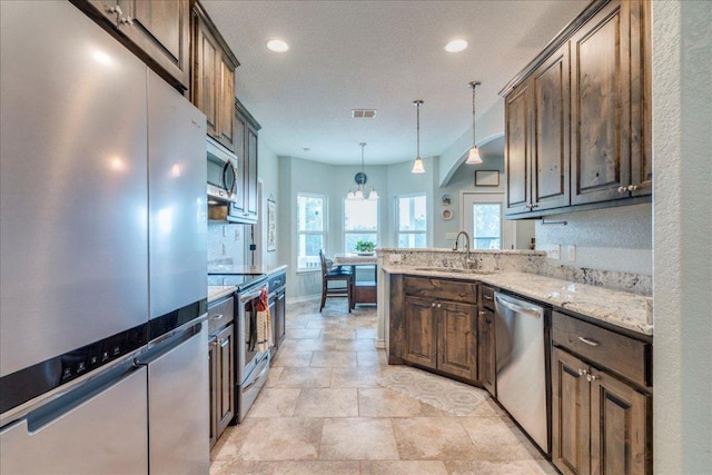 1033 Castleway Rd, New Braunfels, TX 78132 - kitchen with appliances with stainless steel finishes, light stone counters, decorative light fixtures, dark brown cabinets, and recessed lighting