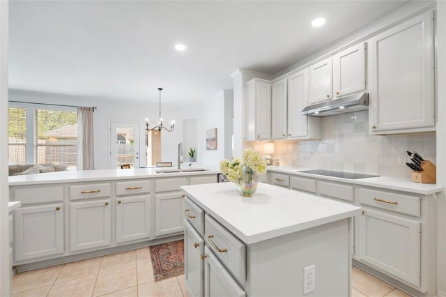 11817 Lake Stone Dr, Austin, TX 78738 - kitchen with under cabinet range hood, a sink, a peninsula, a center island, and light tile patterned floors