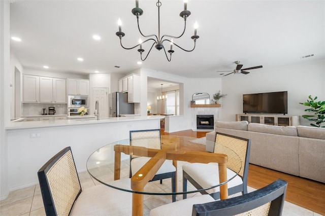 11817 Lake Stone Dr, Austin, TX 78738 - dining space with a chandelier, a fireplace, a ceiling fan, and recessed lighting