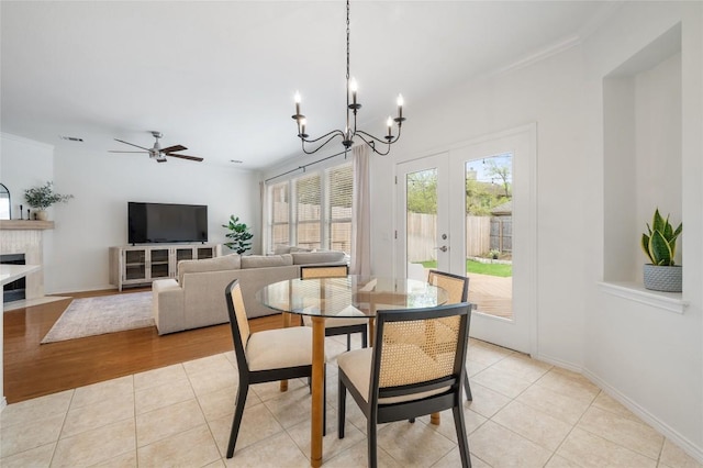 11817 Lake Stone Dr, Austin, TX 78738 - dining space featuring a chandelier, french doors, ceiling fan, light tile patterned flooring, and a tiled fireplace