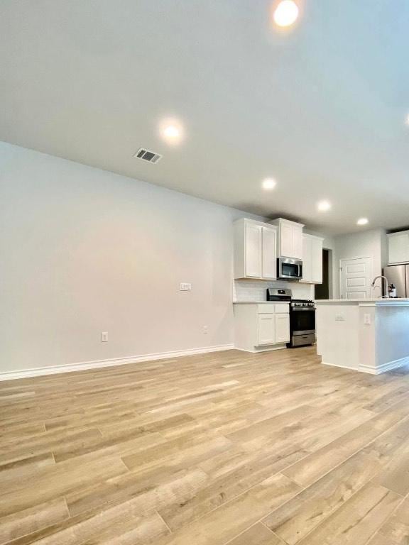 11713 Caithness Way, Austin, TX 78754 - kitchen featuring appliances with stainless steel finishes, open floor plan, light wood-type flooring, baseboards, and white cabinets