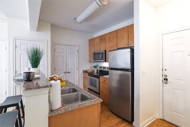 2502 Leon St Unit 208, Austin, TX 78705 - kitchen with appliances with stainless steel finishes, brown cabinetry, light wood-style floors, and a sink