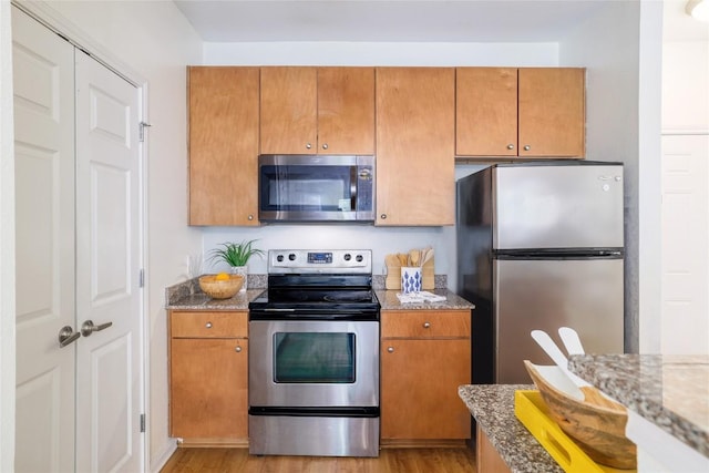2502 Leon St Unit 208, Austin, TX 78705 - kitchen with appliances with stainless steel finishes, light wood-style floors, light stone countertops, and brown cabinetry