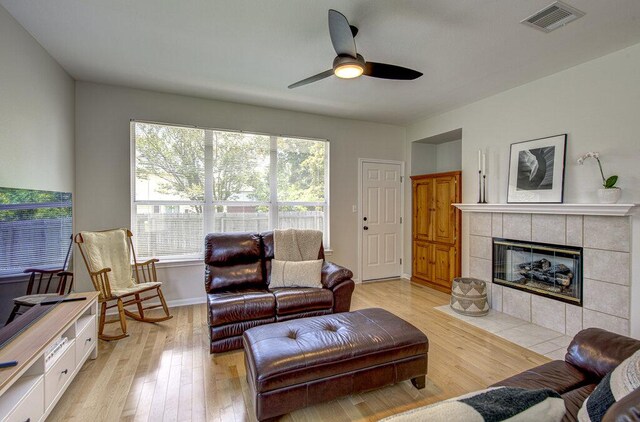 15053 Haley Holw, Austin, TX 78728 - living room with light wood-type flooring, ceiling fan, a tile fireplace, and baseboards