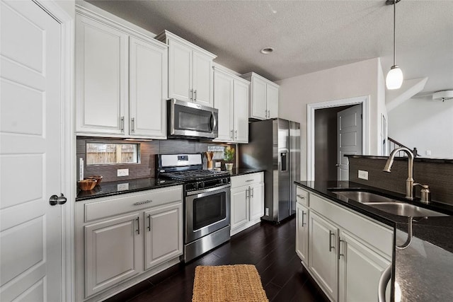 7709 Menchaca Rd Unit 14, Austin, TX 78745 - kitchen featuring appliances with stainless steel finishes, dark countertops, tasteful backsplash, white cabinets, and pendant lighting