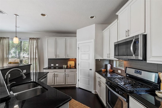 7709 Menchaca Rd Unit 14, Austin, TX 78745 - kitchen featuring stainless steel appliances, dark countertops, white cabinets, hanging light fixtures, and recessed lighting