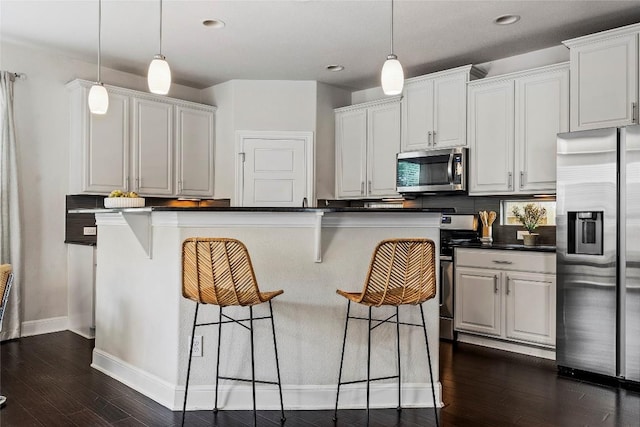 7709 Menchaca Rd Unit 14, Austin, TX 78745 - kitchen with appliances with stainless steel finishes, a kitchen bar, dark countertops, pendant lighting, and dark wood-style floors