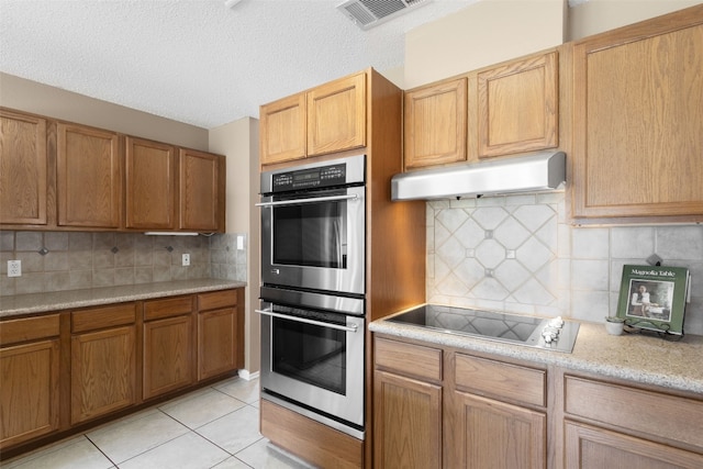 2105 Zeppelin Dr, Cedar Park, TX 78613 - kitchen featuring double oven, under cabinet range hood, black electric stovetop, light tile patterned floors, and backsplash
