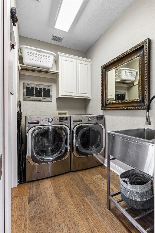 102 Cheerful Ct, Lakeway, TX 78734 - laundry room with cabinet space, washing machine and dryer, and wood finished floors