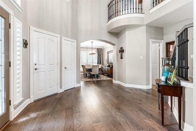 102 Cheerful Ct, Lakeway, TX 78734 - foyer with a high ceiling, arched walkways, dark wood-style flooring, baseboards, and a chandelier