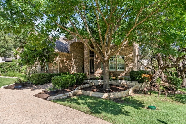 102 Cheerful Ct, Lakeway, TX 78734 - view of property hidden behind natural elements featuring brick siding and a front lawn