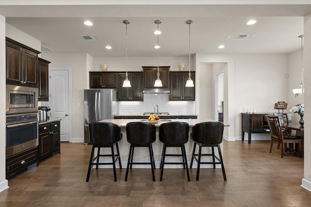 143 Pink Granite Blvd, Dripping Springs, TX 78620 - kitchen featuring stainless steel appliances, decorative backsplash, a kitchen bar, dark brown cabinets, and baseboards