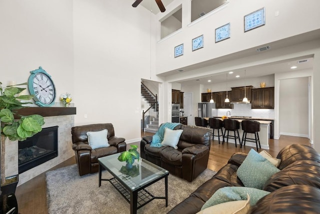 143 Pink Granite Blvd, Dripping Springs, TX 78620 - living area featuring stairway, wood finished floors, ceiling fan, a glass covered fireplace, and a towering ceiling