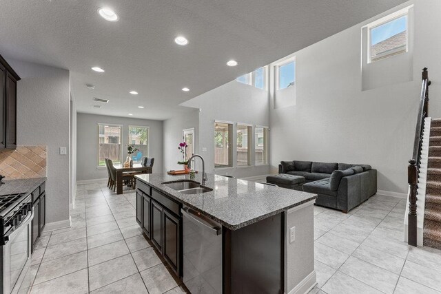 13911 Tribeca, San Antonio, TX 78245 - kitchen featuring a sink, stone countertops, stainless steel dishwasher, black gas range, and an island with sink