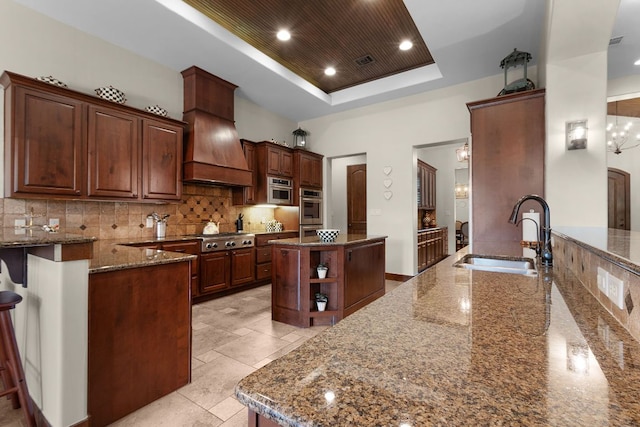 2904 Kodiak Cv, Cedar Park, TX 78613 - kitchen with a tray ceiling, a center island, dark stone counters, a peninsula, and backsplash