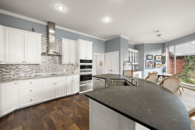10003 Baxter Ln, Austin, TX 78736 - kitchen with wall chimney range hood, appliances with stainless steel finishes, a warming drawer, crown molding, and an island with sink