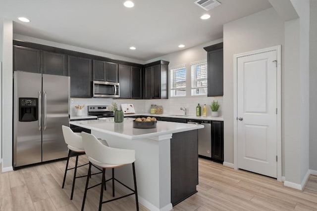 122 Elm Branch Trl, Taylor, TX 76574 - kitchen featuring stainless steel appliances, decorative backsplash, a center island, light wood-style flooring, and recessed lighting