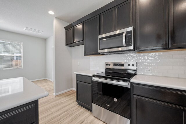 122 Elm Branch Trl, Taylor, TX 76574 - kitchen with appliances with stainless steel finishes, light countertops, backsplash, light wood-style floors, and recessed lighting