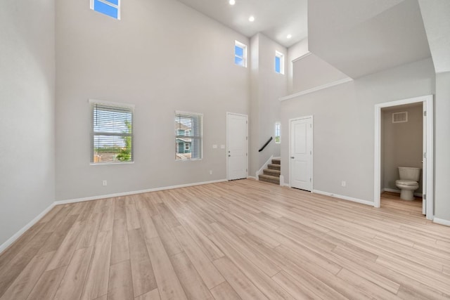 122 Elm Branch Trl, Taylor, TX 76574 - unfurnished living room with stairway, a towering ceiling, plenty of natural light, light wood finished floors, and recessed lighting