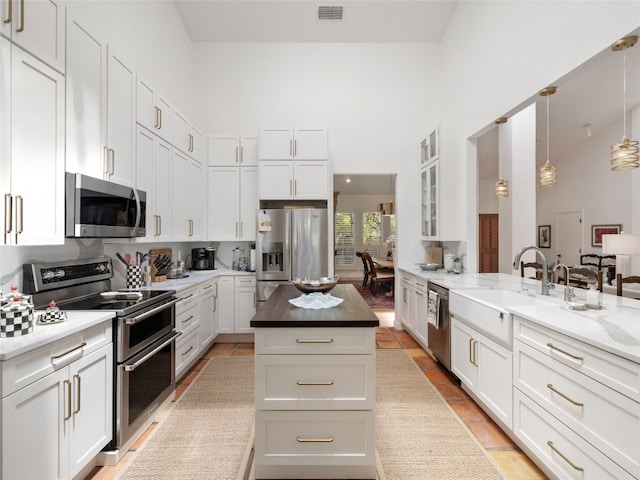 106 Southern Spur, Horseshoe Bay, TX 78657 - kitchen featuring stainless steel appliances, a sink, a high ceiling, white cabinets, and glass insert cabinets