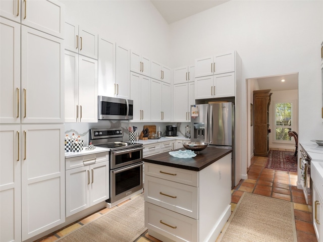 106 Southern Spur, Horseshoe Bay, TX 78657 - kitchen with appliances with stainless steel finishes, wood counters, white cabinetry, a towering ceiling, and a center island