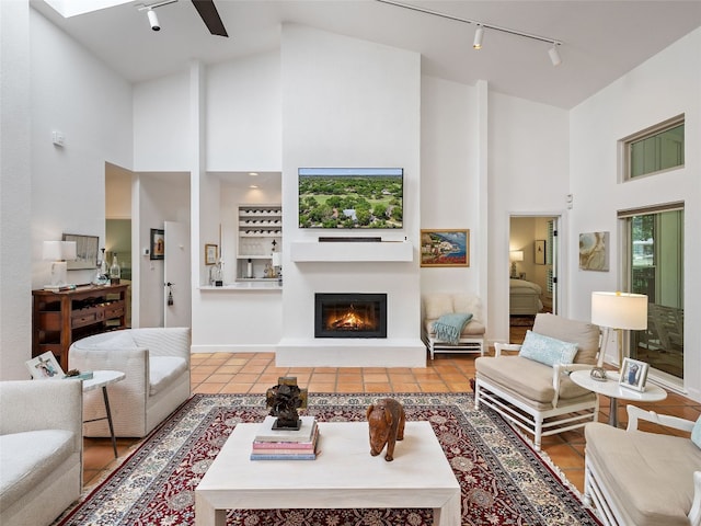 106 Southern Spur, Horseshoe Bay, TX 78657 - living area with rail lighting, high vaulted ceiling, a glass covered fireplace, a ceiling fan, and tile patterned flooring