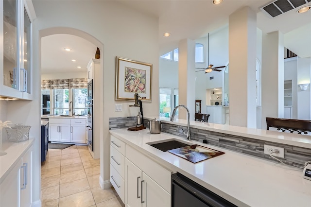 29 Tiburon Dr, The Hills, TX 78738 - kitchen featuring arched walkways, a ceiling fan, white cabinetry, a sink, and light tile patterned floors
