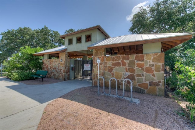 10500 Hendon St, Austin, TX 78748 - view of front facade featuring stone siding, a gate, concrete driveway, and metal roof