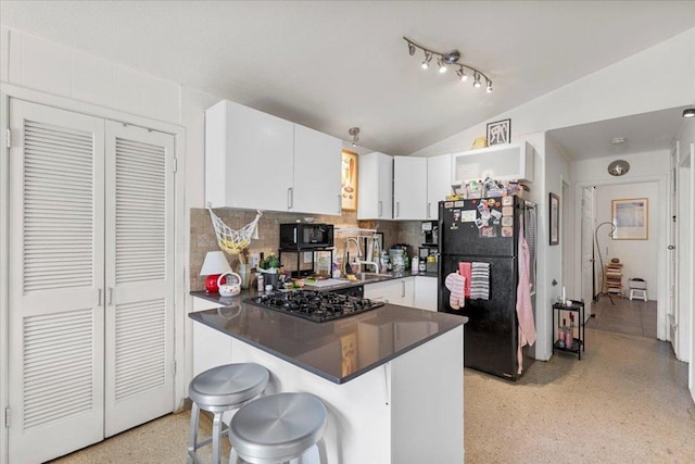 8900 Tina Ct, Austin, TX 78758 - kitchen with black appliances, dark aggregate flooring, lofted ceiling, dark countertops, and a peninsula