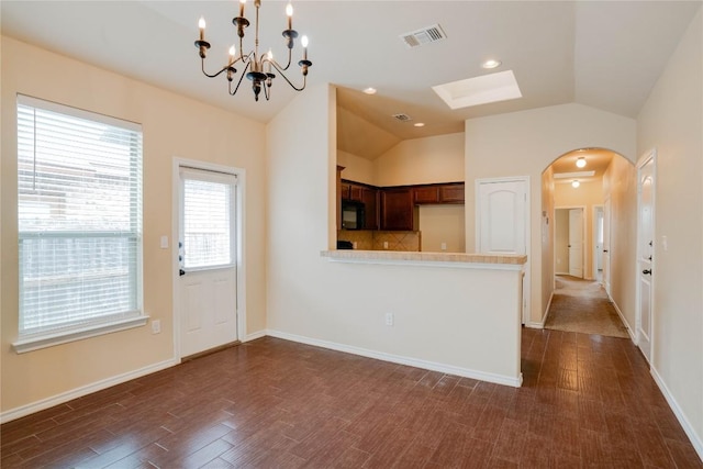 113-119 Creekside Villa Dr, Kyle, TX 78640 - kitchen with black microwave, arched walkways, vaulted ceiling, a peninsula, and light countertops