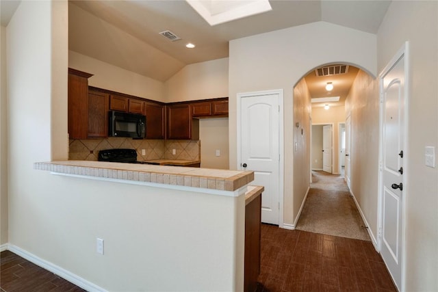 113-119 Creekside Villa Dr, Kyle, TX 78640 - kitchen with black microwave, a peninsula, light countertops, stove, and dark wood-type flooring