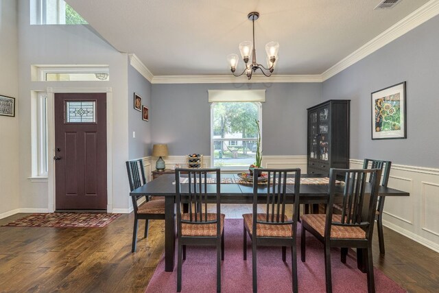 8132 Amelia Cv, Austin, TX 78750 - dining space with dark wood-style floors, a chandelier, crown molding, and a wainscoted wall