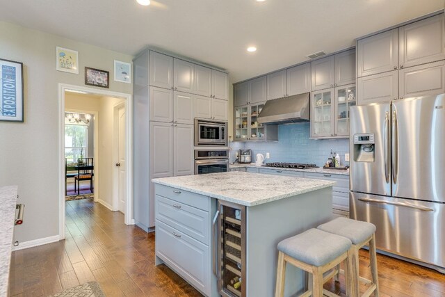 8132 Amelia Cv, Austin, TX 78750 - kitchen with appliances with stainless steel finishes, wine cooler, under cabinet range hood, gray cabinetry, and a kitchen island