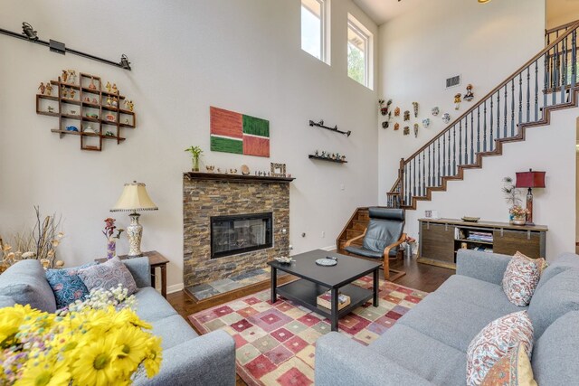 8132 Amelia Cv, Austin, TX 78750 - living room featuring wood finished floors, a high ceiling, stairway, and a fireplace