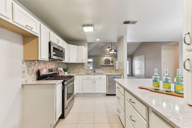 707 Clearwater Trl, Round Rock, TX 78664 - kitchen featuring stainless steel appliances, decorative backsplash, a ceiling fan, white cabinets, and vaulted ceiling