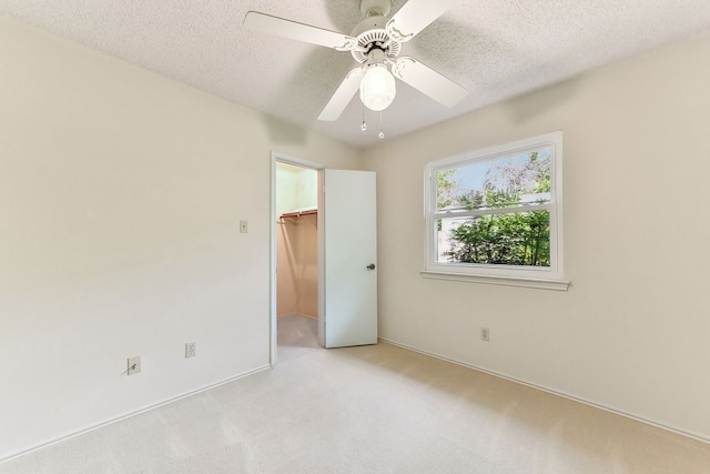 707 Clearwater Trl, Round Rock, TX 78664 - unfurnished bedroom with a walk in closet, a textured ceiling, light carpet, a closet, and ceiling fan