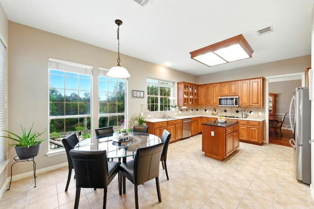 10220 N Chestnut Ridge Rd, Austin, TX 78726 - kitchen featuring appliances with stainless steel finishes, a sink, a center island, brown cabinets, and tasteful backsplash
