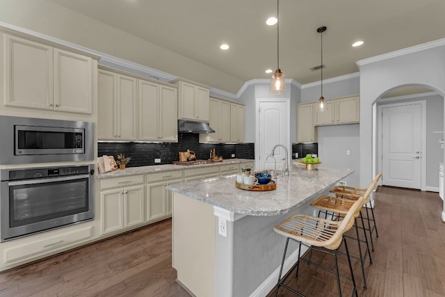 8316 Evelina Trl, Austin, TX 78737 - kitchen with appliances with stainless steel finishes, crown molding, under cabinet range hood, tasteful backsplash, and arched walkways