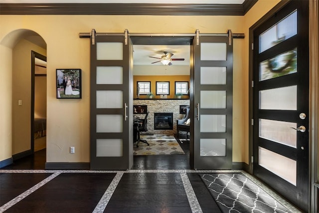 5700 Cherokee Draw Rd, Austin, TX 78738 - entrance foyer featuring a barn door, ceiling fan, a fireplace, crown molding, and arched walkways