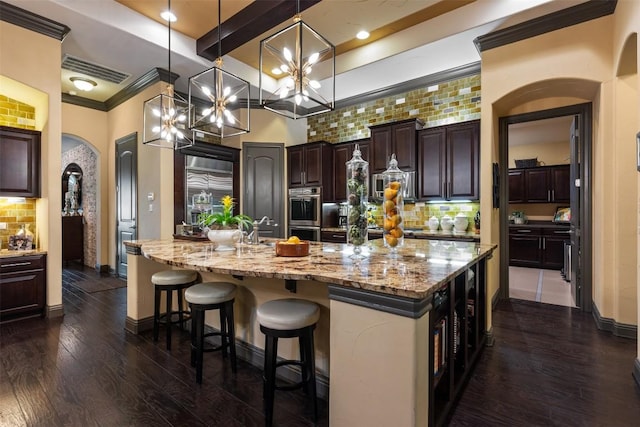 5700 Cherokee Draw Rd, Austin, TX 78738 - kitchen featuring dark brown cabinetry, backsplash, a large island, light stone counters, and beam ceiling