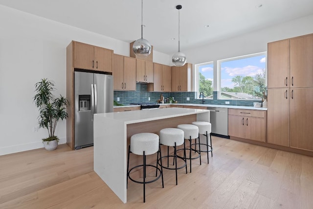 6410 Cannonleague Dr Unit 1, Austin, TX 78745 - kitchen with appliances with stainless steel finishes, light wood-style floors, a kitchen breakfast bar, and tasteful backsplash