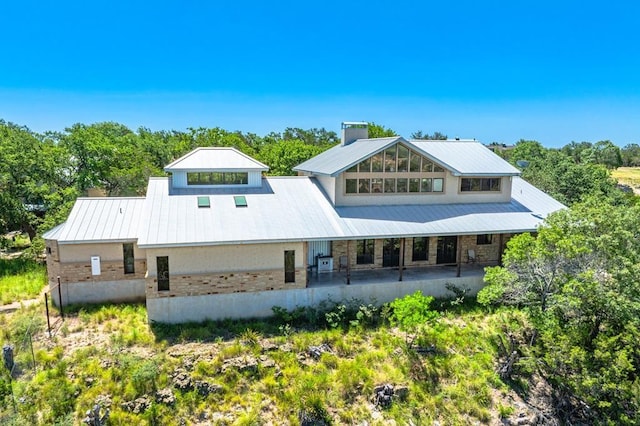 165 Highridge Ln, Fredericksburg, TX 78624 - rear view of property featuring a chimney, brick siding, a metal roof, and covered porch